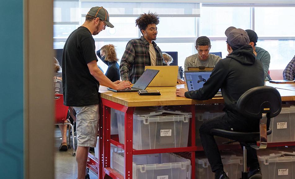 一群学生在工程空间用笔记本电脑工作
